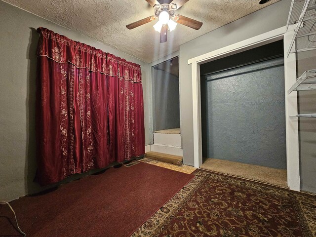 carpeted spare room featuring a textured ceiling and ceiling fan