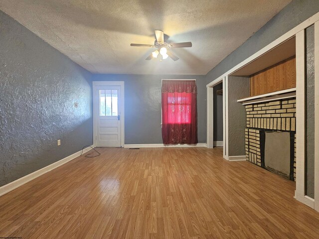 unfurnished living room with hardwood / wood-style flooring, a fireplace, a textured ceiling, and ceiling fan