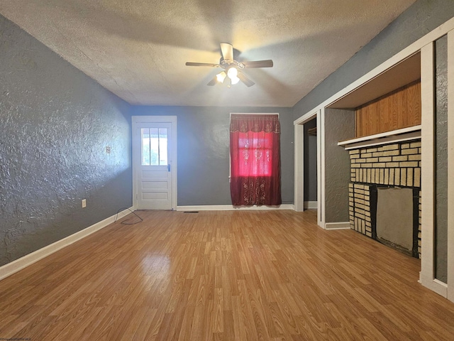 entrance foyer featuring a textured ceiling, a textured wall, a fireplace, wood finished floors, and baseboards