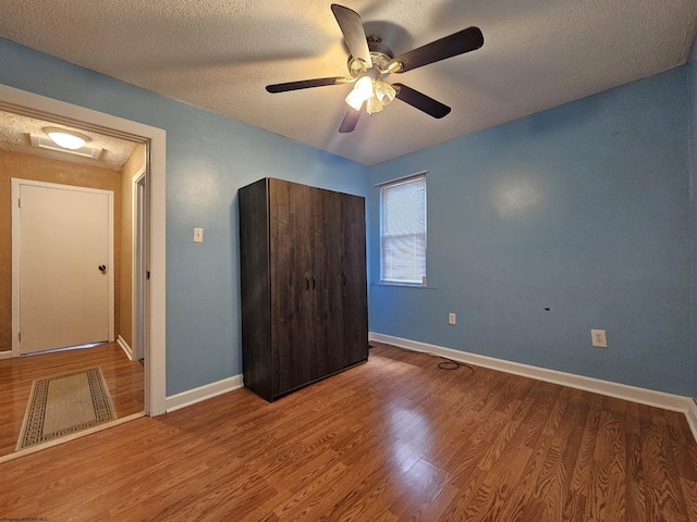 unfurnished bedroom featuring hardwood / wood-style floors, ceiling fan, and a textured ceiling