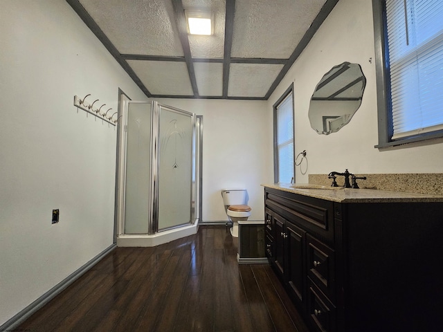 bathroom featuring toilet, vanity, a shower stall, wood finished floors, and baseboards