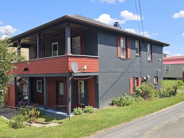 view of front facade with brick siding, a front lawn, and a chimney