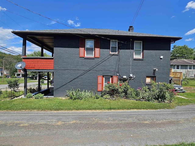 view of side of property with brick siding, a lawn, and a chimney