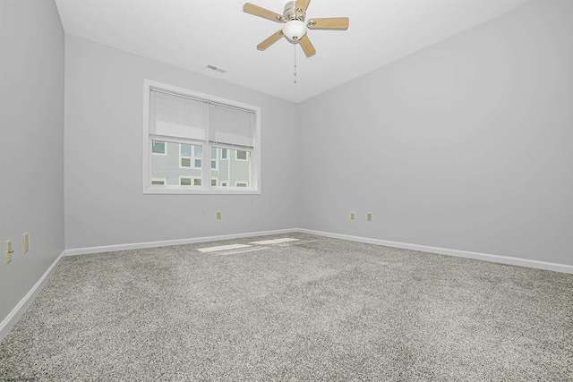 spare room with carpet floors, visible vents, baseboards, and a ceiling fan