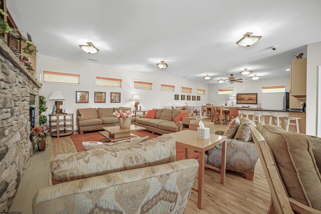 living room with a fireplace, ceiling fan, and light wood-type flooring