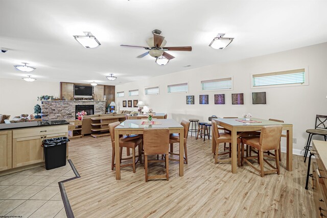 dining room featuring light hardwood / wood-style floors, ceiling fan, and a fireplace