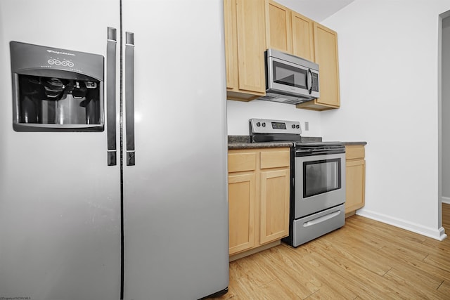 kitchen with stainless steel appliances, baseboards, light wood-type flooring, light brown cabinetry, and dark countertops