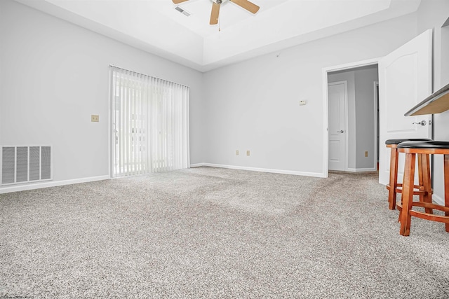 carpeted living room featuring ceiling fan and a raised ceiling