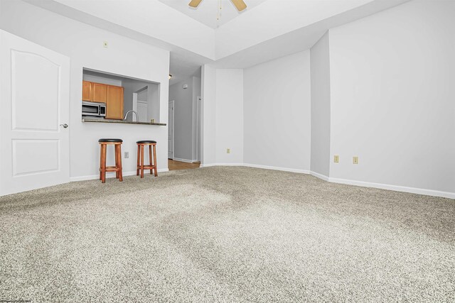 unfurnished living room featuring ceiling fan and carpet floors