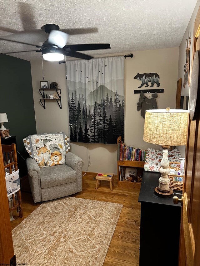 living room with a textured ceiling, ceiling fan, and hardwood / wood-style floors