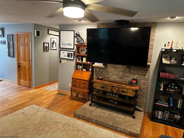 living area with wood finished floors, visible vents, baseboards, ceiling fan, and a textured ceiling