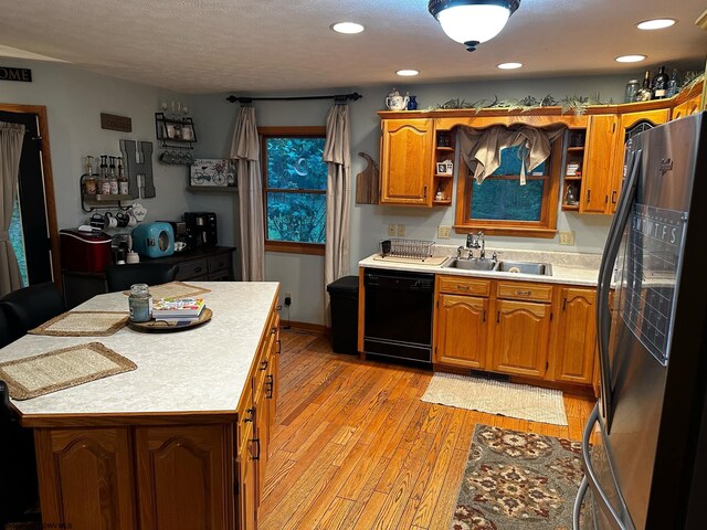 kitchen featuring sink, light wood-type flooring, black appliances, and a center island