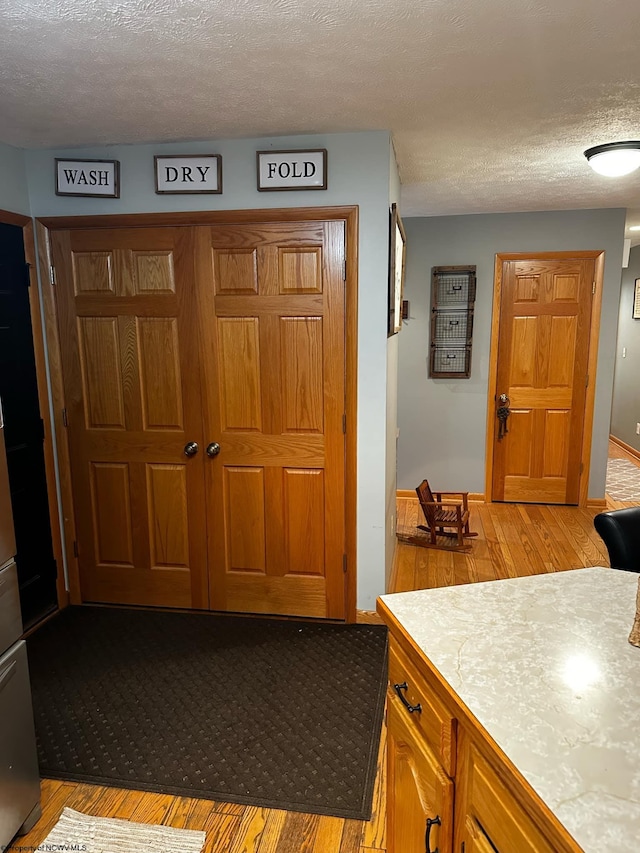 kitchen with light wood-type flooring and a textured ceiling