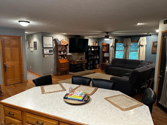 dining space featuring ceiling fan, baseboards, a textured ceiling, and wood finished floors