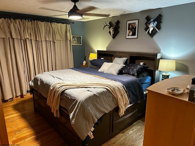 bedroom with light hardwood / wood-style floors, ceiling fan, and a textured ceiling