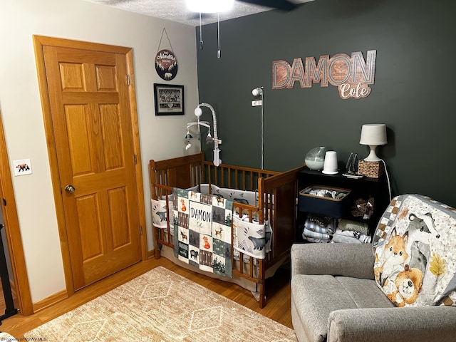 bedroom featuring a textured ceiling, baseboards, and wood finished floors