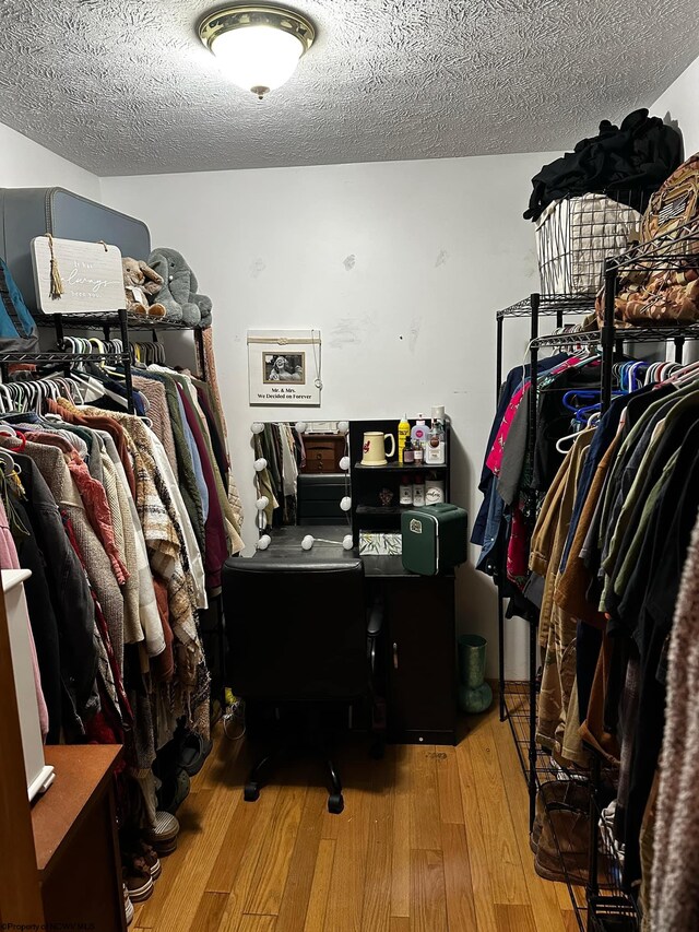 walk in closet with light hardwood / wood-style floors