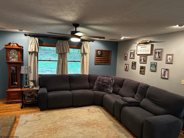 living room featuring hardwood / wood-style floors, ceiling fan, and a textured ceiling