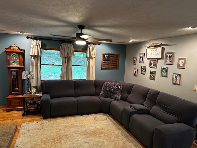 living room with a ceiling fan, wood finished floors, and a textured ceiling