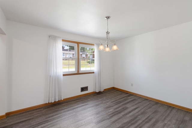 unfurnished room featuring visible vents, dark wood finished floors, a notable chandelier, and baseboards