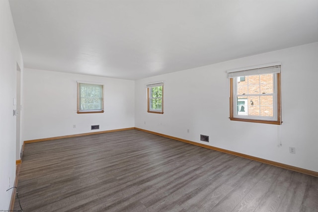 spare room featuring wood finished floors, visible vents, and baseboards