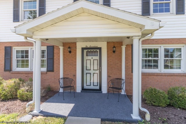 view of exterior entry featuring a patio area and brick siding