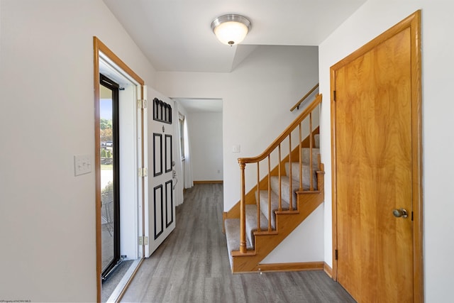 entrance foyer with stairway, wood finished floors, and baseboards