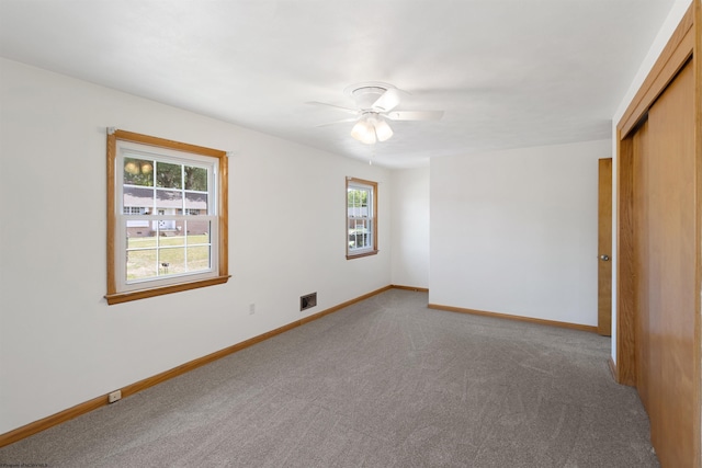 spare room with carpet, visible vents, ceiling fan, and baseboards