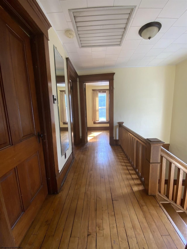 hallway featuring visible vents, light wood-type flooring, and an upstairs landing