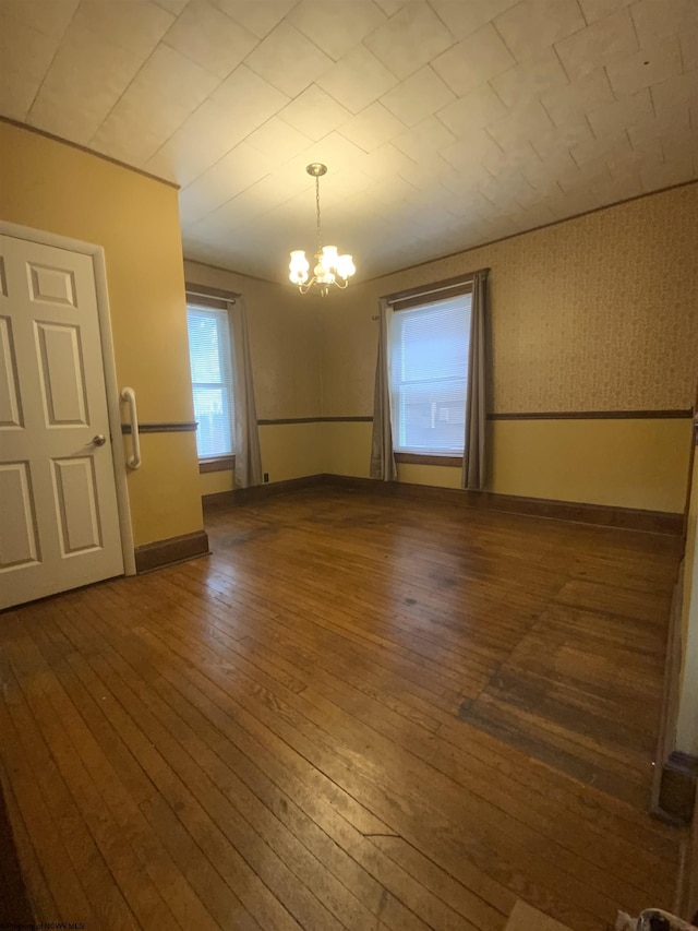 unfurnished dining area with a chandelier, dark wood finished floors, and baseboards