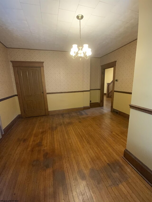 empty room featuring hardwood / wood-style floors and a notable chandelier