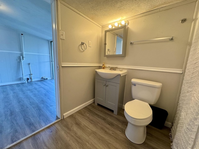 full bath featuring a textured ceiling, toilet, wood finished floors, vanity, and a shower