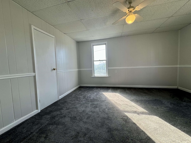 unfurnished room with a drop ceiling and dark carpet