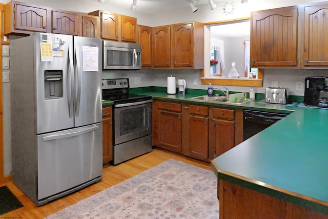 kitchen featuring light wood-type flooring, sink, stainless steel appliances, and rail lighting