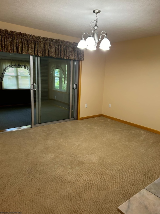 spare room featuring baseboards, carpet flooring, and a notable chandelier