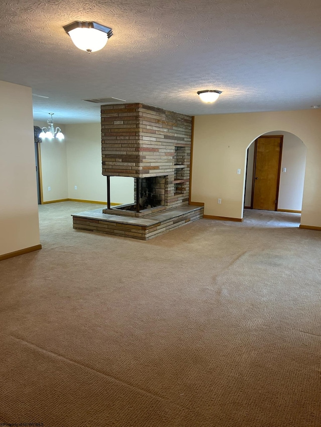 unfurnished living room featuring a textured ceiling, a fireplace, arched walkways, and carpet flooring