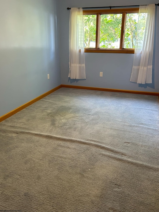 spare room featuring carpet and baseboards