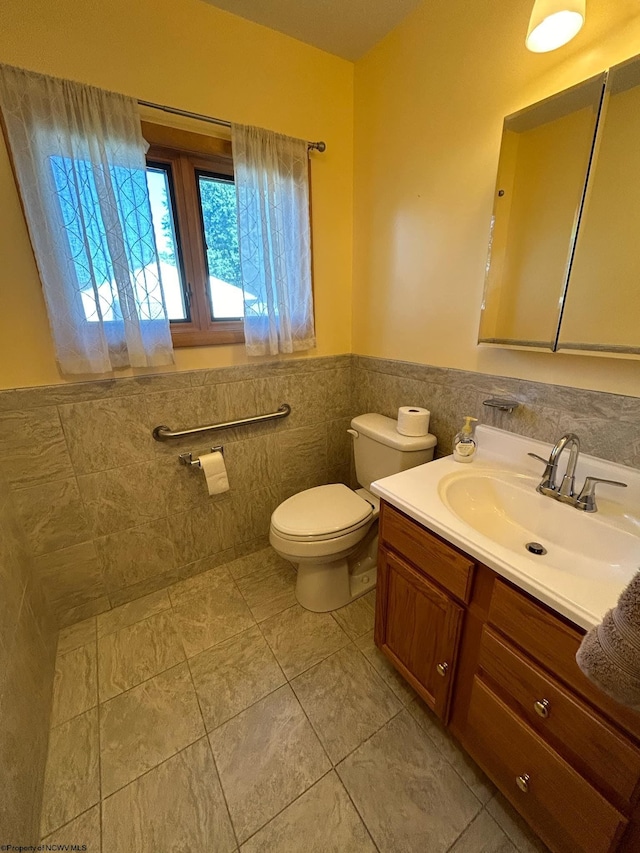 bathroom featuring toilet, vanity, tile walls, and wainscoting