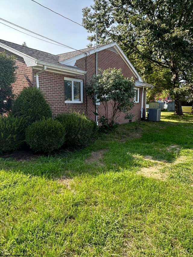 view of side of property featuring cooling unit and a yard