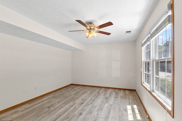 empty room featuring ceiling fan, plenty of natural light, and light hardwood / wood-style flooring