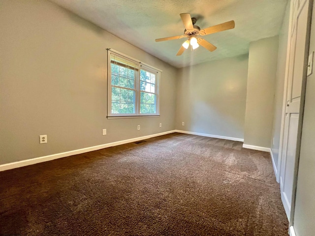 spare room featuring ceiling fan and dark colored carpet