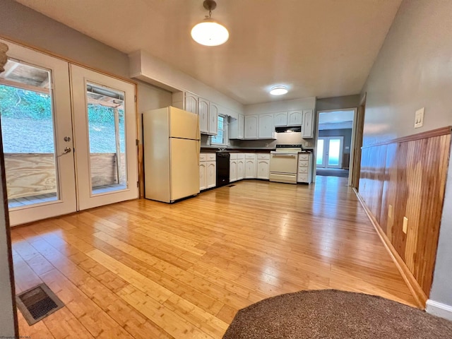 kitchen featuring french doors, white appliances, light hardwood / wood-style floors, and wood walls