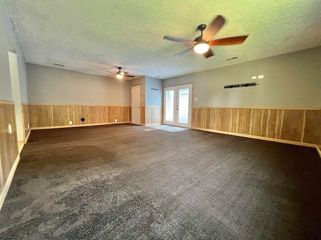 spare room featuring dark colored carpet, french doors, a textured ceiling, and ceiling fan