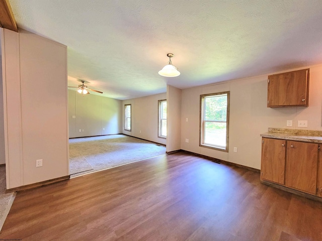 unfurnished living room with dark wood-style floors, a ceiling fan, baseboards, and a textured ceiling