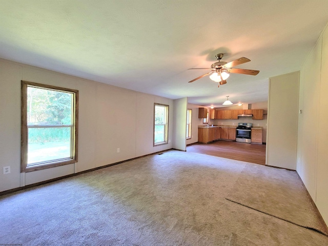 unfurnished living room with ceiling fan, a healthy amount of sunlight, and light colored carpet