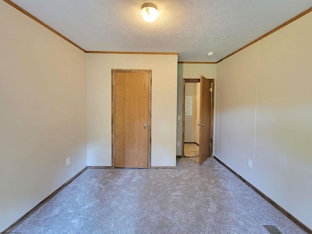 unfurnished bedroom featuring a textured ceiling, carpet floors, and ornamental molding