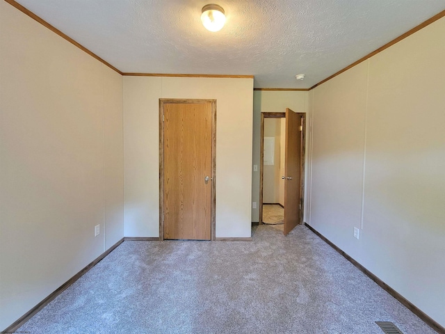 unfurnished bedroom featuring carpet floors, visible vents, ornamental molding, and a textured ceiling