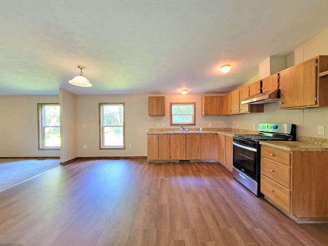 kitchen with gas range, sink, a textured ceiling, dark wood-type flooring, and hanging light fixtures