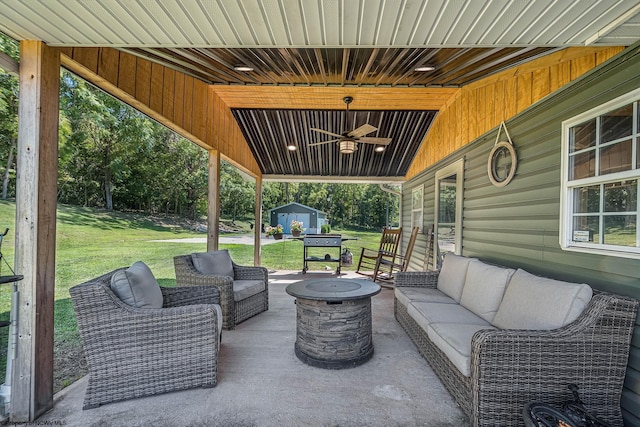 view of patio featuring ceiling fan, a shed, and an outdoor living space with a fire pit