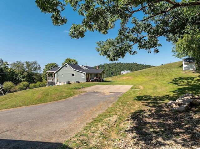 exterior space featuring driveway, a front lawn, and a chimney